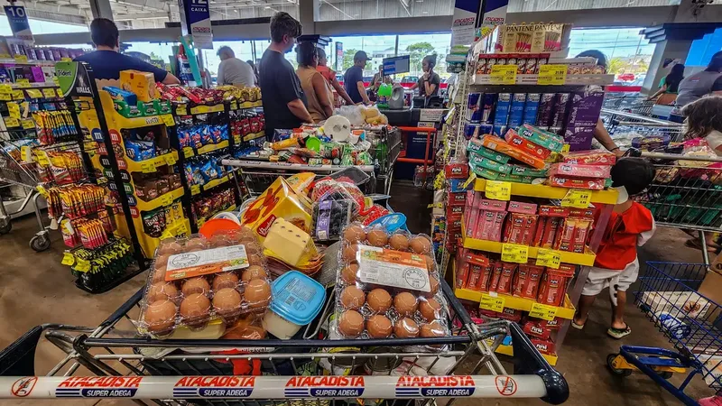 12/06/2026 - Brasília - Consumidores enfrentam longas filas nos caixas de um grande mercado atacadista para finalizar suas compras. Diante do cenário de inflação acumulada e da constante alta de preços nos itens básicos…