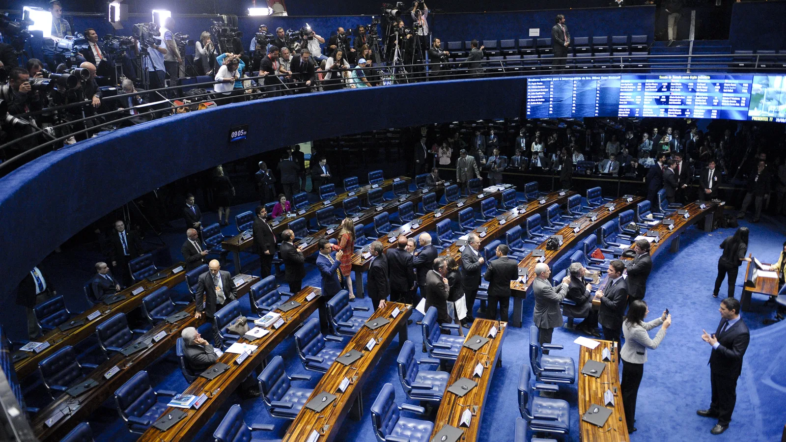 Vista do alto do plenário do Senado, com bancadas azuis e senadores em pé